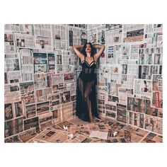 a woman standing in front of a wall covered with newspaper pages and photoshopped to look like she has her hands on her head