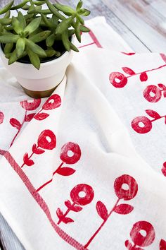 a small potted plant sitting on top of a white cloth covered in red flowers