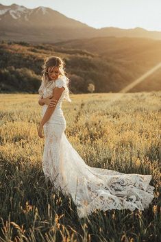 a woman standing in a field with mountains in the background