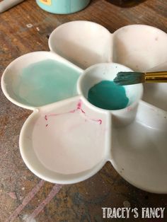 a white flower shaped bowl with paint in it