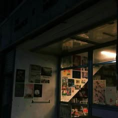 a store front with posters on the wall and lights shining in from the window at night