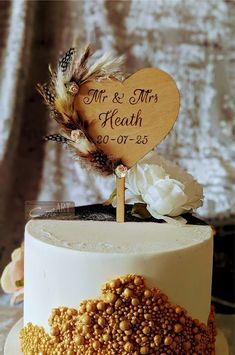 a wedding cake is decorated with gold and white beads on the top, along with a wooden sign that says mr & mrs health