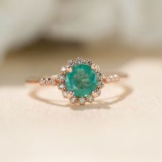 a close up of a ring with a green stone in the middle and diamonds around it