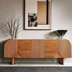 a wooden cabinet sitting in the middle of a living room next to a painting on the wall