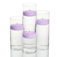 six glass vases with candles in them on a white background, one is filled with water and the other has a purple candle