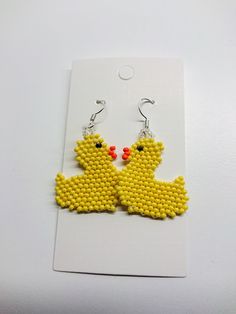 two yellow birds made out of seed beads on a white card with silver earwires