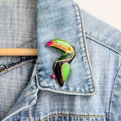 Add a touch of whimsical charm to any outfit with this Statement Toucan Bird Brooch.  This unique lapel pin is the perfect gift for any nature-loving bird nerd in your life.  Handcrafted with care, this nature jewelry piece makes for a thoughtful and memorable friend gift.  Other nature and animal brooches you can find here: https://www.etsy.com/shop/JewelryKatMade?section_id=28373902 Measurements of the brooch are: 5.4 x 4.9 cm.  Please keep in mind that colors may vary slightly from those view Unique Green Enamel Pin Gift, Unique Multicolor Enamel Pin For Gift, Unique Multicolor Enamel Pin Gift, Green Enamel Pin Brooch For Gift, Green Brooch Enamel Pin For Gift, Green Enamel Brooch Pin As Gift, Toucan Bird, Animal Brooch, Bird Brooch