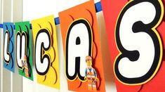 the word abc and j are spelled in lego letters on colorful paper banners hanging from a wall