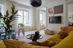 a living room filled with yellow furniture and lots of window sill covered in plants