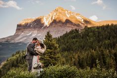 a bride and groom standing in front of a mountain