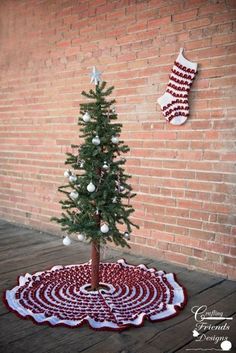 a small christmas tree on a rug in front of a brick wall