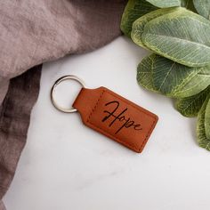 a leather keychain with the word faith written on it next to some leaves