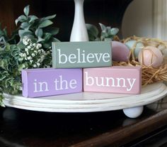 a wooden block that says believe in the bunny on top of a plate with flowers