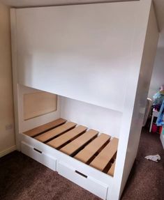 a white bunk bed with two drawers underneath it and an open shelf above the bed