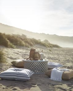 a table and some pillows on the beach