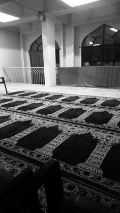 a black and white photo of an area with rugs on the floor, benches in the background