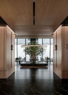 a large room with wooden walls and black marble flooring, along with plants in the center