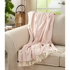 a pink blanket sitting on top of a couch next to a window