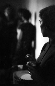 a black and white photo of a woman looking at her cell phone in the dark