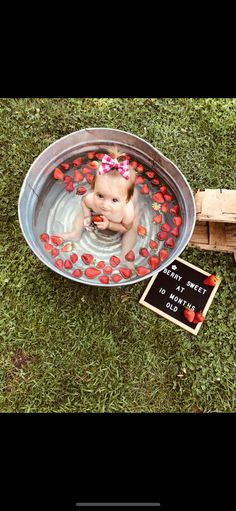 a baby in a metal tub with hearts on it and a chalkboard sign next to it