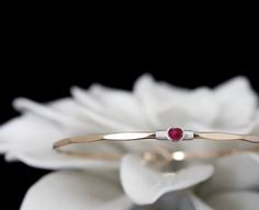 "My signature solitaire bangle, a timeless bracelet featuring a vibrant lab created Ruby, July's traditional birthstone. These gems exhibit a vivid and saturated magenta pink color and a semi-translucent body. The bracelet features a locking hook and eye closure. The gems used in this design measure approximately 3.5mm.  METAL OPTIONS  Select your choice from the dropdown menu. If the Two Toned option is selected please use the personalization field to specify your combination.  FINISH OPTIONS Adjustable Fine Jewelry Bangle For Anniversary, Elegant May Birthstone Jewelry With Tension Setting, Classic Gemstone Bangle For Anniversary, Stackable Round Band Bracelets For Anniversary, Elegant Red Stackable Jewelry, Stackable Round Band Bracelets As Gift, Jubilee Bracelet Jewelry For Anniversary With May Birthstone, Stackable Bracelets As Gift, Anniversary Jubilee Bracelet With May Birthstone