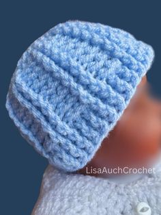 a blue crocheted hat on top of a doll's head