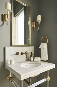 a bathroom sink sitting under a mirror next to a wall mounted faucet with lights on it