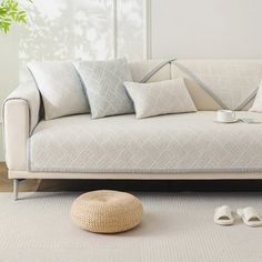 a white couch sitting on top of a wooden floor next to a potted plant