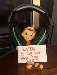 a stuffed animal sitting on top of a wooden table next to a sign that says listen so you can hear from god