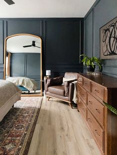 a bedroom with blue walls and wooden furniture in front of a large mirror on the wall