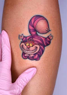 a woman's thigh with a cartoon character tattoo on it and a pink glove