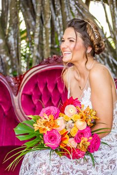 a woman sitting on a pink couch with flowers in her hair and holding a bouquet