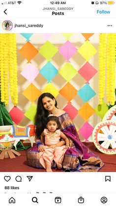 two women and a baby posing for a photo in front of colorful wall paper decorations