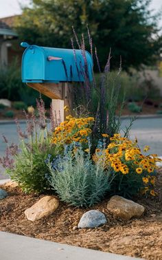 a blue mailbox sitting in the middle of a flower bed