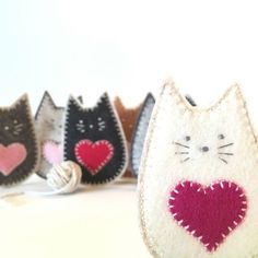 three small cat purses with hearts on them sitting next to each other in front of a white background