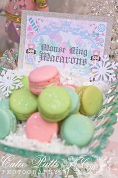 a bowl filled with macaroons sitting on top of a table next to a sign