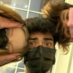 three people wearing face masks in front of a mirror