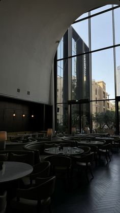 the interior of a restaurant with large windows and tables in front of it, along with tall buildings