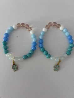 two bracelets with charms on them sitting on a table