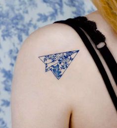 a woman with a tattoo on her shoulder has a blue triangle in the shape of an origami