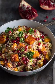 a white bowl filled with food next to two pomegranates