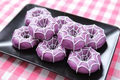 purple sprinkled donuts on a black plate with pink and white checkered tablecloth