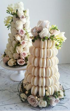 two tiered wedding cakes with flowers on the top and bottom, sitting on a marble table