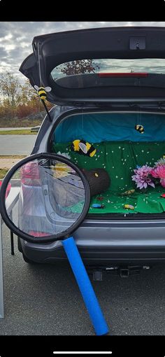 the back end of a car with its trunk open and flowers in it's bed