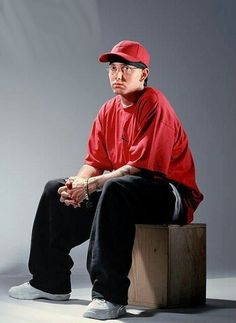 a man sitting on top of a piece of luggage wearing a red shirt and hat