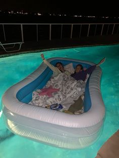 two people laying on an inflatable raft at the edge of a swimming pool