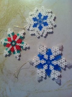 two snowflakes made out of plastic beads are sitting on a counter top