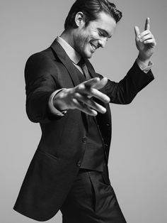 a black and white photo of a man in a suit pointing at something with his finger