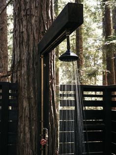 a shower head is attached to the side of a wooden fence in front of a tree