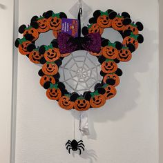 a halloween wreath hanging on the wall with pumpkins and spider web in front of it